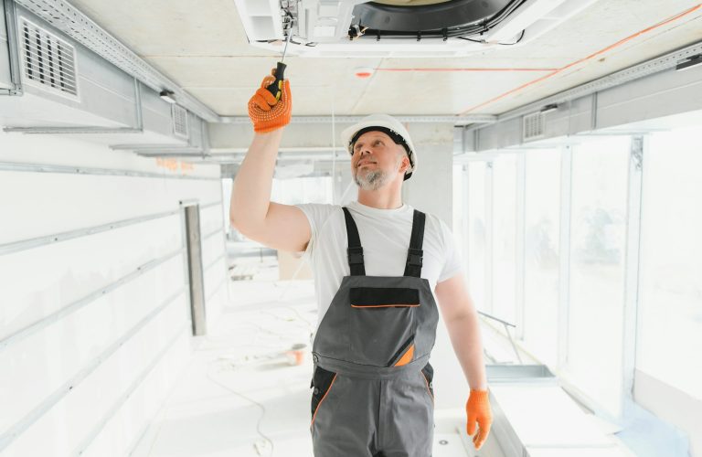 Worker repairing ceiling air conditioning unit